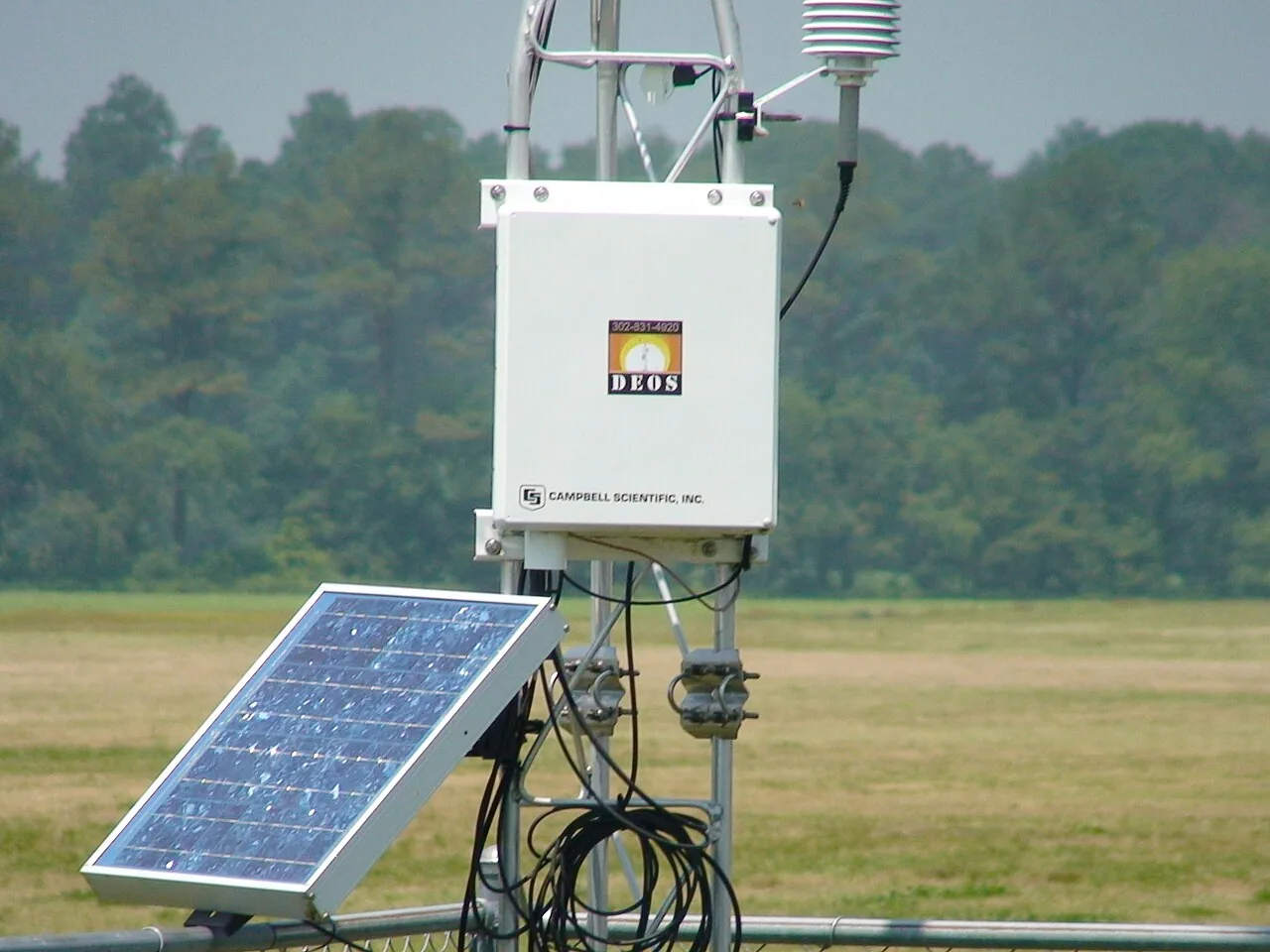 A solar-powered automatic weather station with logger enclosure, radiation shield and sensors standing in an open field