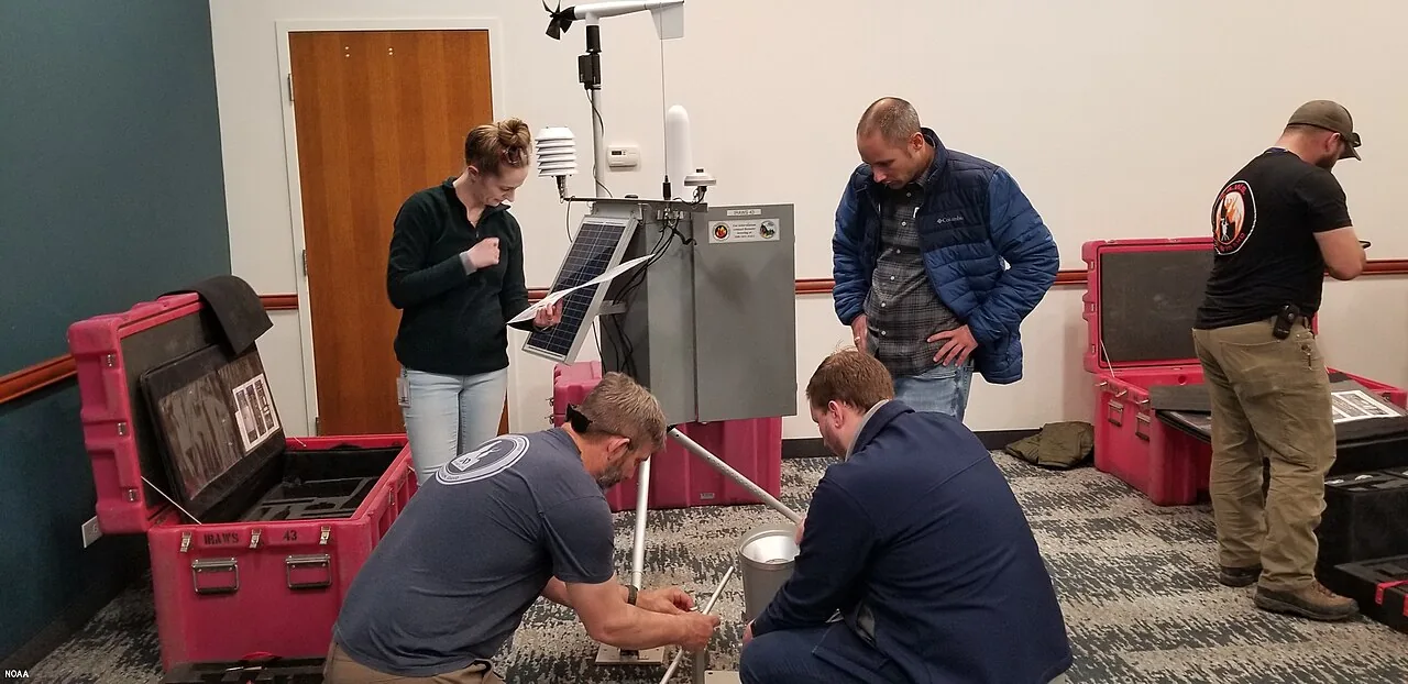 Technicians assembling and checking a portable automatic weather station with its transport cases open